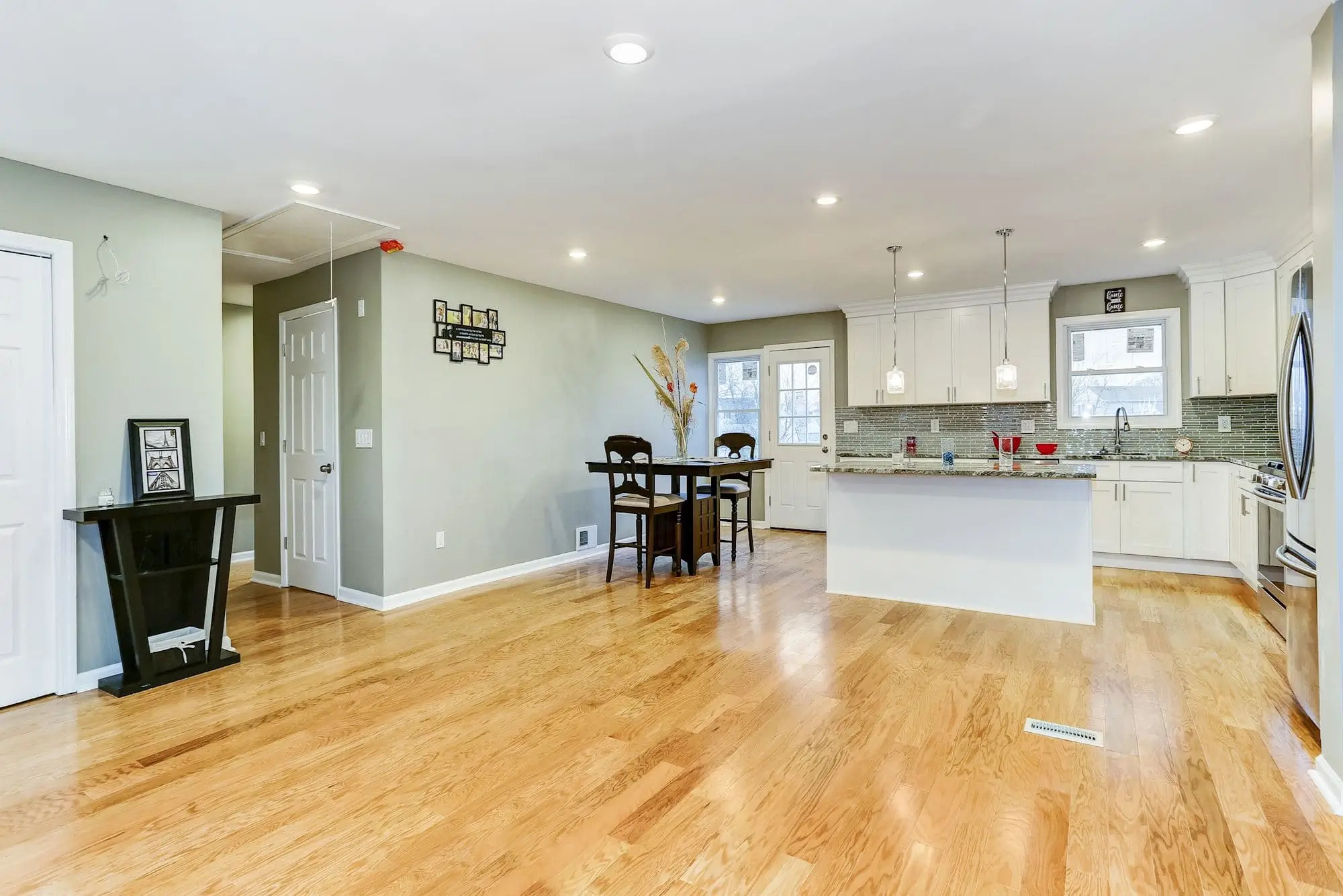 Open-plan space with white kitchen, island and dark dining table