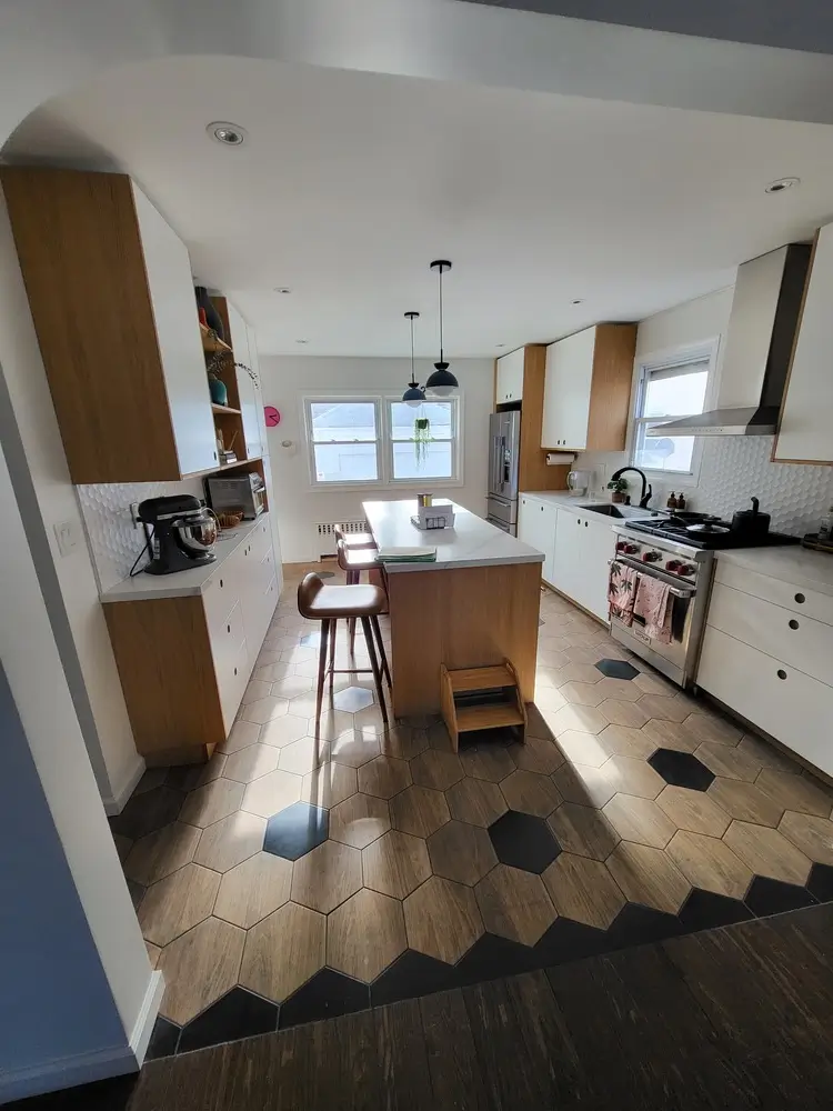 Spacious kitchen with light wood center island and geometric tile flooring