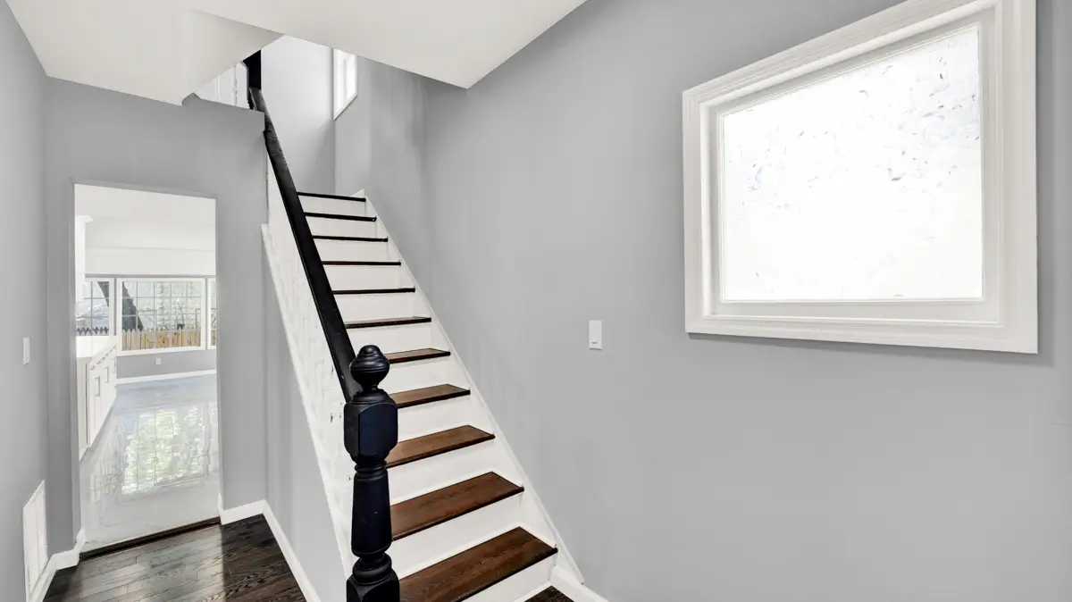 Interior staircase with dark handrail and light wood treads