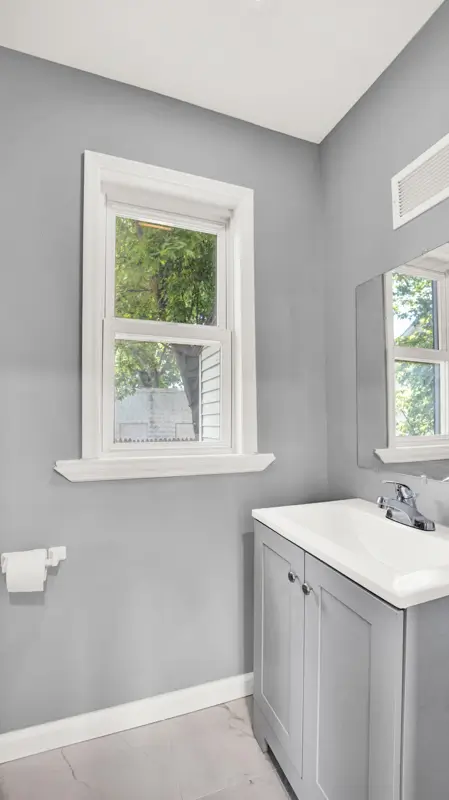 Bathroom with gray walls, white sash window and gray vanity