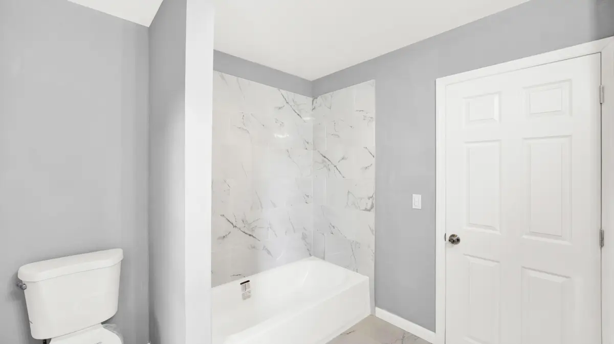 Small bathroom with white marble bathtub and white door