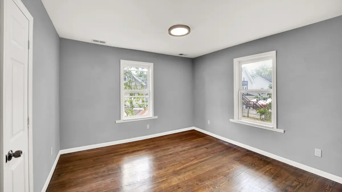 Room with gray walls, dark wood floor and two windows