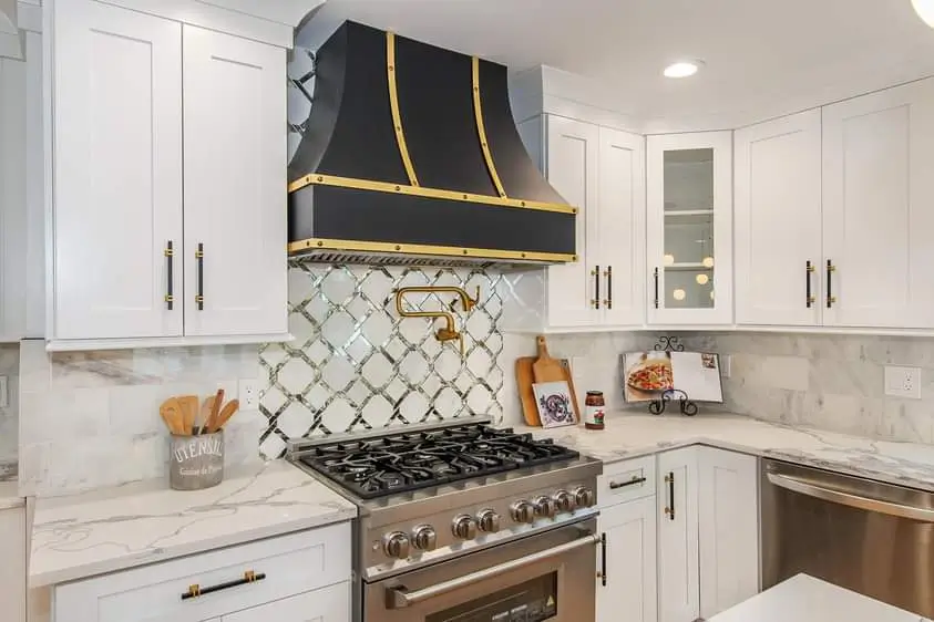 Elegant kitchen with black extractor hood and gold details on stove top