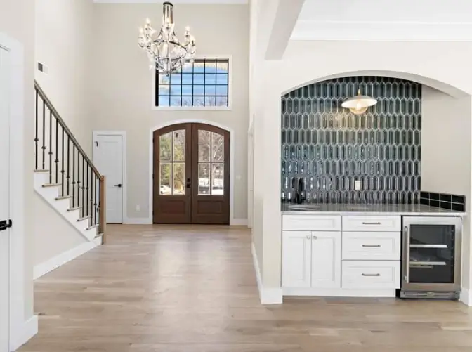 Entrance foyer with chandelier, tiled bar and staircase